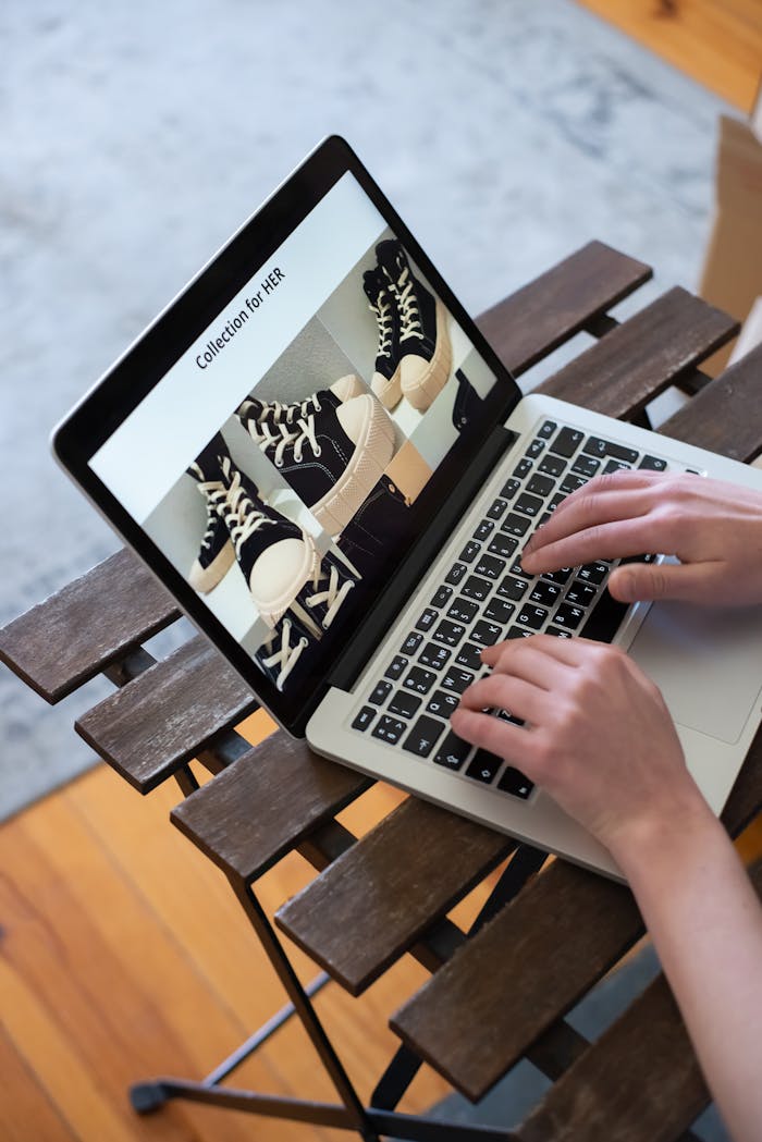 digital Hands browsing sneakers on laptop, showcasing online store shopping experience.